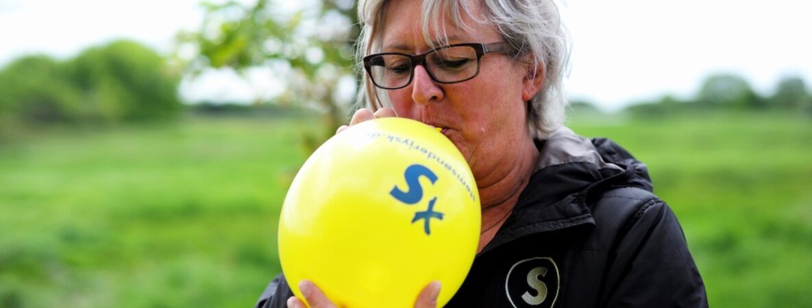 Jette Erichsen bläst einen gelben Luftballon der Schleswigschen Partei auf.