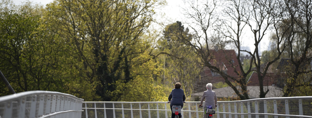Zwei Frauen fahren mit dem Fahrrad über eine Brücke.