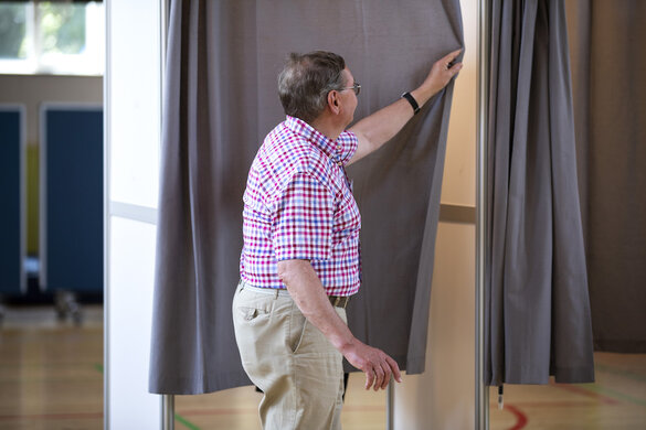 Alf Ingfeldt zieht den Vorhang der Abstimmungskabine zu.