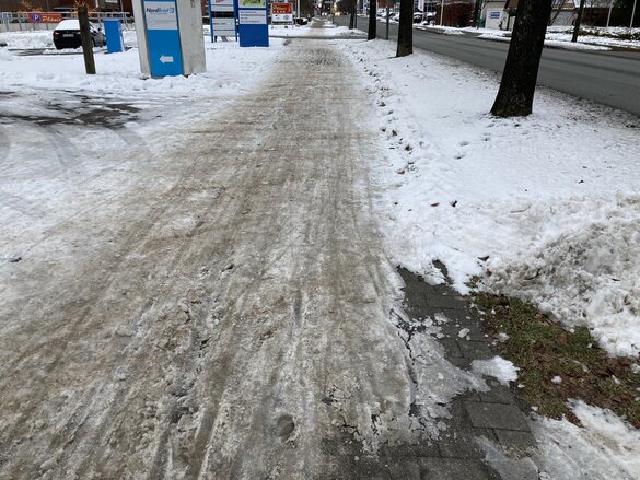 Während die Fahrbahn frei ist, liegt auf dem Radweg eine dicke Eisschicht.