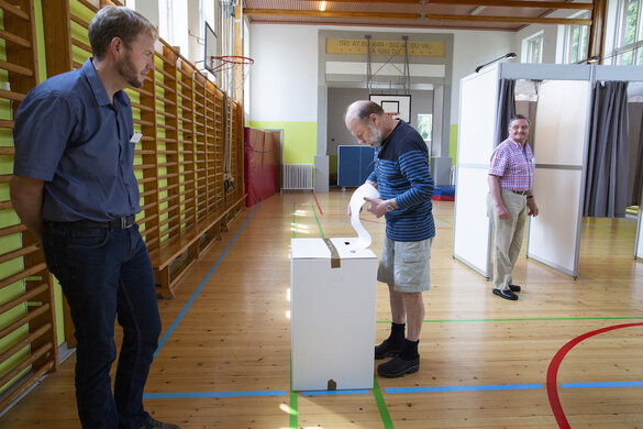 Jens Knudsen steckt seinen Wahlzettel in den Schlitz der Wahlurne.