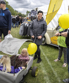 Zwei kleine Mädchen in einem überdachten Bollerwagen haben am Stand der Schleswigschen Partei einen gelben Ballon erhalten.