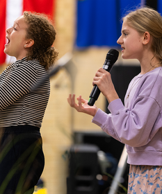 Zwei junge Mädchen stehen auf der Bühne und singen in ein Mikrofon