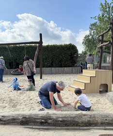 Kinder und Großeltern spielen im Sand