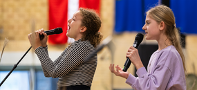 Zwei junge Mädchen stehen auf der Bühne und singen in ein Mikrofon
