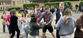 Schüler- und Lehrerschaft tanzt auf dem Hof