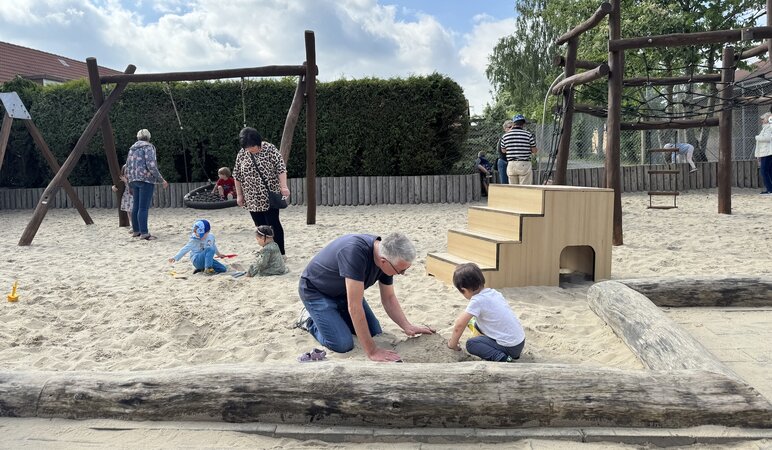 Kinder und Großeltern spielen im Sand